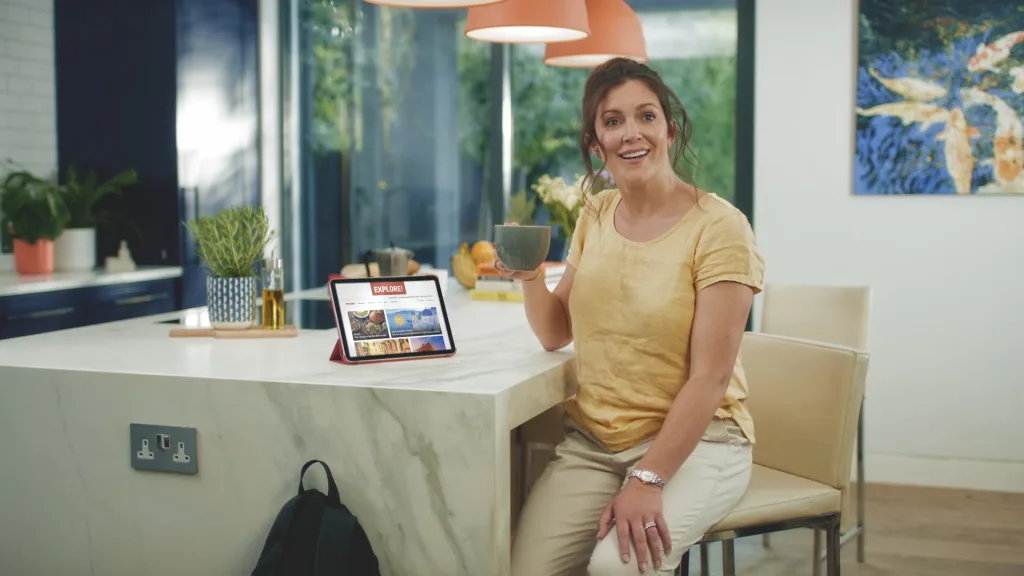 Woman in a kitchen holding a mug beside a tablet
