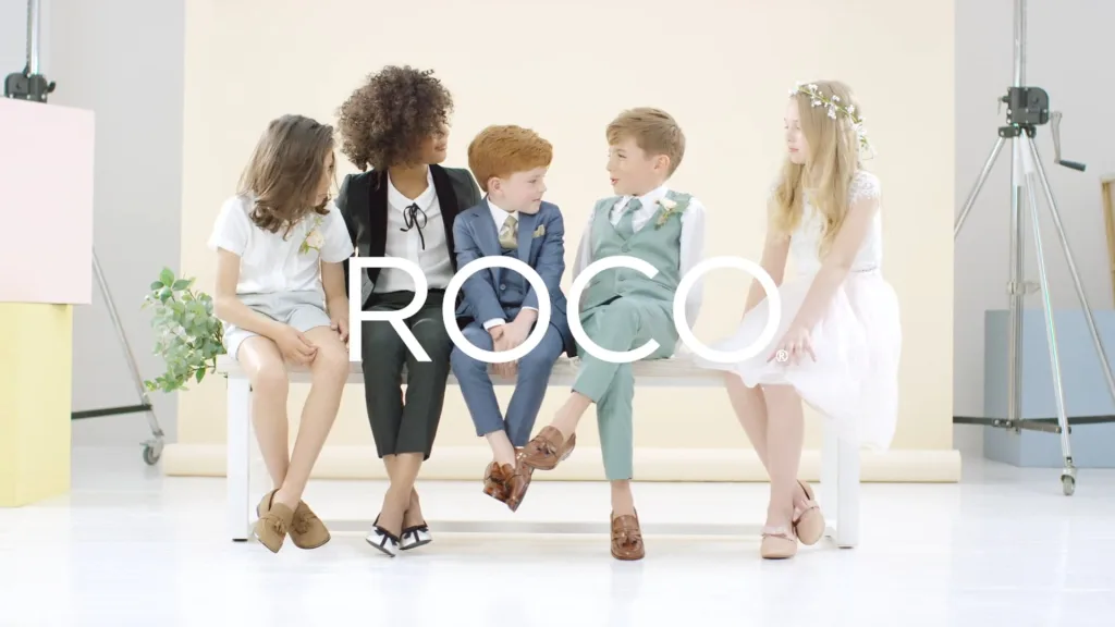 Children in formalwear seated on a bench for Roco