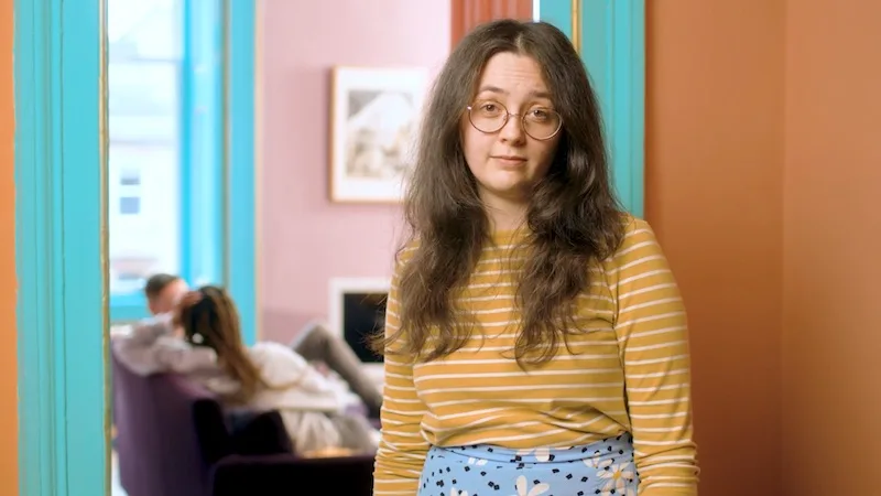Young woman in a striped top in a brightly coloured room