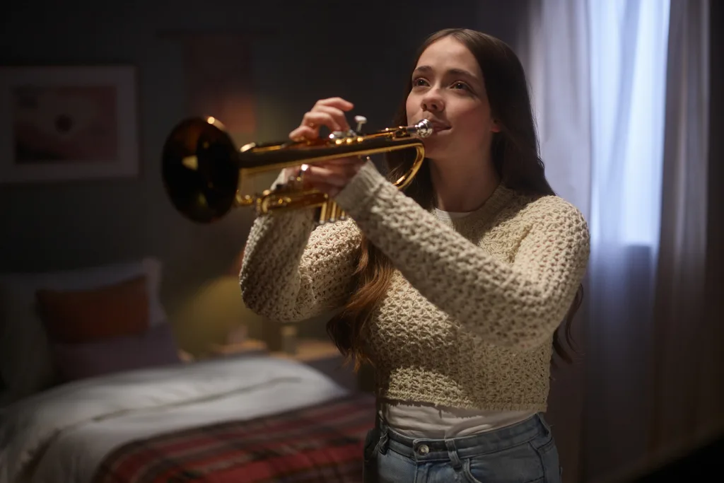 Woman playing trumpet in a bedroom